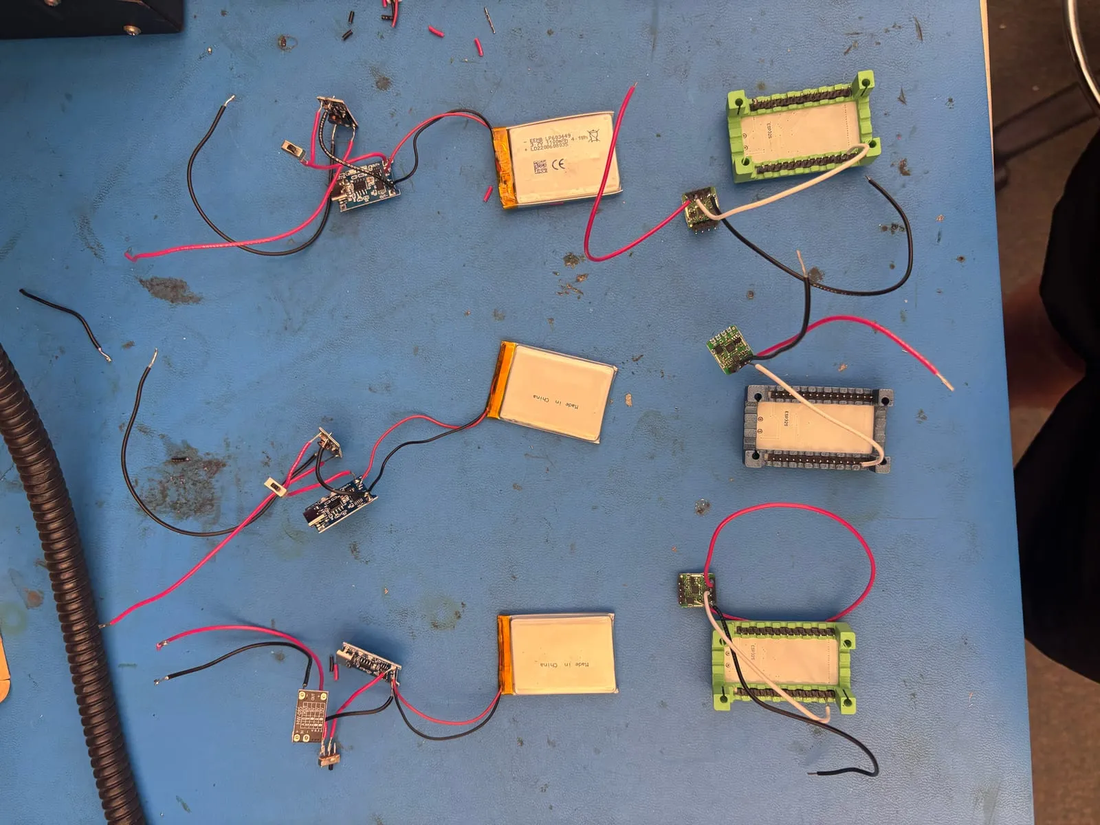 Four battery packs wired to charging modules and boost converters on a workbench.